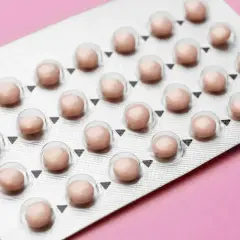 Blister opakowania tabletek antykoncepcyjnych na różowym tle.