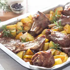 Agnello al forno marinato con patate e rosmarino, un piatto succulento e profumato, pronto per essere gustato.