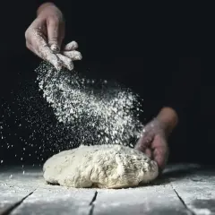 Händer strör mjöl över deg. Skillnaden mellan vetemjöl och vetemjöl special blir tydlig i bakningen.