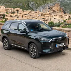 Ebro S800 PHEV, un SUV moderno, aparcado en una carretera con un pueblo pintoresco de fondo.
