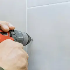 Mani esperte usano un trapano per forare la ceramica senza romperla, mostrando la tecnica corretta.