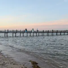 Piękna egipska pogoda we wrześniu. Długie molo na spokojnym morzu, piasek na plaży i pastelowe niebo.