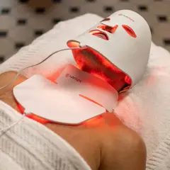 En person får behandling med en vit led mask ansikte som lyser rött.