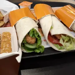 Trzy mcwrap klasyczny z kurczakiem, warzywami i sosem. Obok frytki i paluszki serowe. Idealny zestaw na szybki posiłek, z uwzględnieniem kcal.