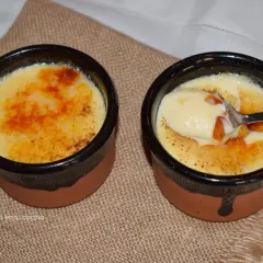 Dos deliciosas cremas catalanas, una con una cucharada lista para disfrutar, sobre una tela rústica.