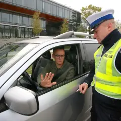 Policjant rozmawia z kierowcą, który może otrzymać zatrzymanie prawa jazdy na 3 miesiące.