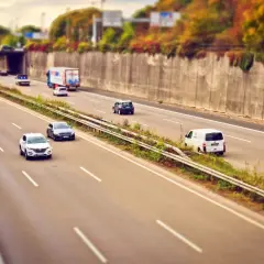 Voitures et camion circulent sur l'autoroute A85, sous un pont, avec des arbres aux couleurs d'automne sur les talus.