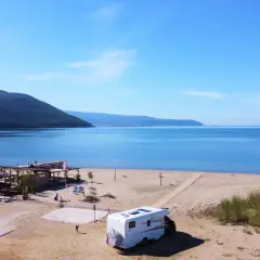 Kamper na piaszczystej plaży w Grecji kontynentalnej, z widokiem na spokojne morze i zalesione wzgórza. Idealne miejsce na wakacje.