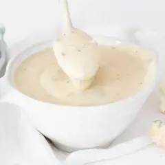 Cremosa salsa gorgonzola servida en un cuenco blanco, con trozos de queso gorgonzola esparcidos alrededor.