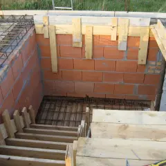 Budowa schodów drewnianych: szalunek z desek i cegieł, zbrojenie pod beton.