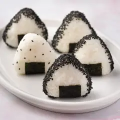 Five triangular onigiri bento, some coated in black sesame seeds, sit on a white plate, ready for a delicious meal.