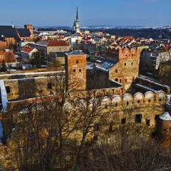 Ruiny zamku w Ząbkowicach Śląskich, z charakterystycznymi ceglanymi murami i wieżami, na tle zimowego krajobrazu miasta.