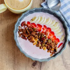 Un delicioso tazón de batido de bayas de acai con fresas, plátano, granola y almendras.