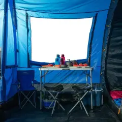 Wnętrze niebieskiego namiotu z rozstawionym stołem, krzesłami i śpiworami. Doskonała wodoodporność namiotu zapewnia komfortowe warunki.