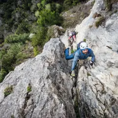 Mann klettert gesichert im Klettersteig, die Rastschlinge ist am Gurt befestigt.