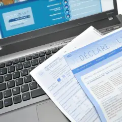 Documents fiscaux sur un ordinateur portable, dont une déclaration de revenus et un guide pour la lettre changement adresse impots.