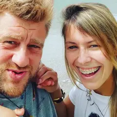 Tomasz Jakubiak z żoną i dzieckiem na wakacjach. Uśmiechnięta para cieszy się wspólnym czasem.