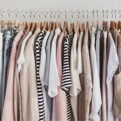 Kleiderständer mit einer Auswahl an Kleidungsstücken in neutralen Farben, die sich gut für eine Capsule Wardrobe eignen.