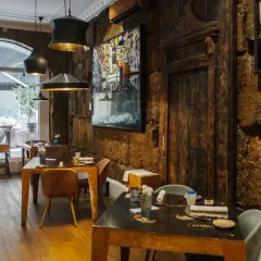 Interno di un ristorante con tavoli apparecchiati e pareti in pietra grezza. Un'atmosfera che fa pensare ai migliori ristoranti di Palermo.
