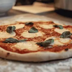 Une délicieuse pizza Margherita, avec sa pâte à pizza maison, prête à être dégustée. Un vrai délice pour les amateurs de pain et de bonnes choses.