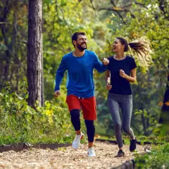 Szczęśliwa para cieszy się wspólnym trail run w jesiennym lesie.