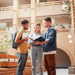 Drei Studierende planen ihren Auslandssemester Master in einem modernen Gebäude.