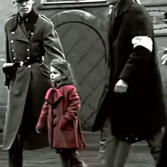 Mała dziewczynka w czerwonym płaszczyku idzie obok żołnierzy.