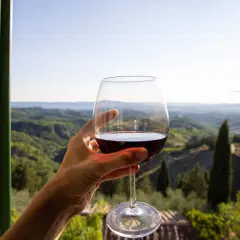 Un bicchiere di vino rosso, con il paesaggio del Val d'Orcia sullo sfondo. Un momento di puro piacere.