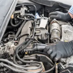 Mechanik w rękawiczkach naprawia silnik Renault, być może z powodu błędu dtc p0141.