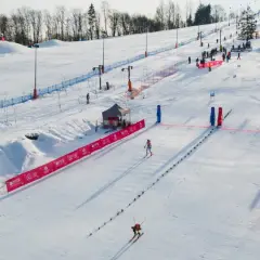 Widok na stok narciarski w Szczawnicy. Narciarze zjeżdżają po ośnieżonym zboczu, a czerwone bandy wyznaczają trasę.