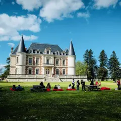 Visite d'un magnifique château dans le Médoc, avec des gens profitant du soleil sur la pelouse.