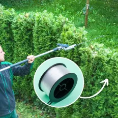 Mężczyzna w słuchawkach przycina żywopłot z tui od dołu, używając długiego nożyc. W kółku szpulka żyłki.