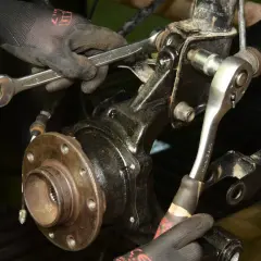 Mechanik dokręca śruby przy piaście, gdzie znajduje się łożysko w kole.