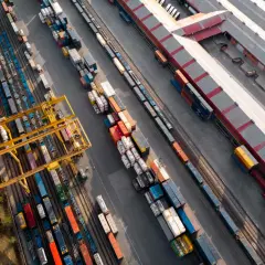 Widok z lotu ptaka na terminal kolejowy, gdzie odbywa się transport intermodalny. Żurawie przeładowują kontenery między pociągami a ciężarówkami.