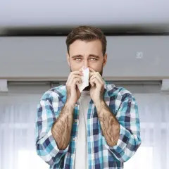 Hombre con pañuelo en la nariz, con aire acondicionado de fondo. Podría ser que se puede tener alergia al aire acondicionado.