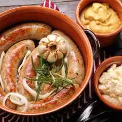 Pyszna biała kiełbasa pieczona w cebuli i musztardzie, podana z chrzanem i żurawiną.