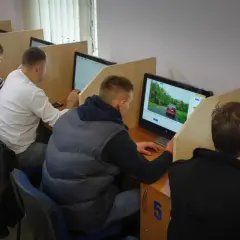 Osoby siedzą przy komputerach, rozwiązując testy. Tak wygląda egzamin teoretyczny na prawo jazdy.