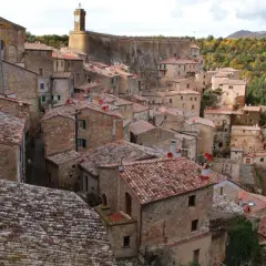 Sorano, Toscana: un borgo medievale arroccato su una rupe tufacea, con tetti rossi e case in pietra che si fondono con il paesaggio autunnale.