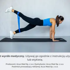 Kobieta ćwiczy z taśmą oporową na macie. Czy można ćwiczyć z zakwasami? Tak, lekkie ćwiczenia mogą pomóc.