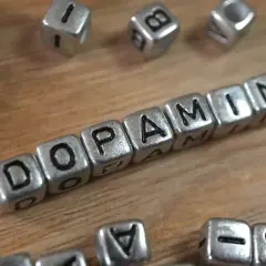 Cubos plateados forman la palabra "DOPAMINE". Descubre cómo aumentar tu dopamina para sentirte mejor.