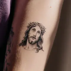 Ein Porträt von Jesus mit Dornenkrone, ein Beispiel für minimalistische Tattoos, auf einem Arm.