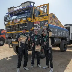 Trzej członkowie zespołu KAMENA Rally Team pozują z pucharami przed ciężarówką DAF.