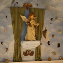 Engelsfiguren schweben vor einer Wolkenwand im **Engelmuseum Engelskirchen**. Eine große Engelsfigur thront auf einer Wolke.