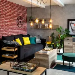 Męski pokój inspiracje: loftowy styl z ceglaną ścianą, czarną kanapą, drewnianymi meblami i industrialnymi lampami.