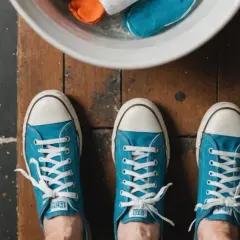 Niebieskie trampki na drewnianej podłodze. W misce obok pomarańczowe i niebieskie szmatki. Jak zapobiec, żeby buty nie farbowały?