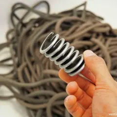 Ein Werkzeug mit Bürsten, das zum kletterseil waschen dient, wird in der Hand gehalten. Im Hintergrund liegt ein Haufen Seile.
