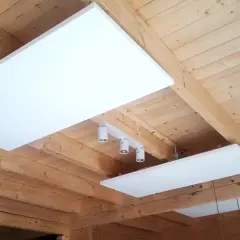 Białe panele grzewcze zamontowane na drewnianym suficie.