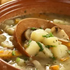 Zupa ziemniaczana przepis babci: sycąca, domowa zupa z ziemniaków, marchewki i grzybów, podana w glinianej misce z drewnianą łyżką.