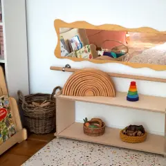 Holzspielzeug, Bücher und Körbe für ein gemütliches Kinderzimmer einrichten. Ein Holzregal mit Regenbogen und Stapelturm.