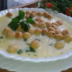 Aksamitna zupa z groszkiem ptysiowym, udekorowana natką pietruszki, czeka na spróbowanie.